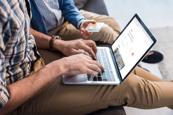 QUIIV, UCRÂNIA - OUTUBRO 15, 2019: visão recortada do pai judeu usando laptop com site airbnb e filho segurando cartão de crédito — Fotografia de Stock