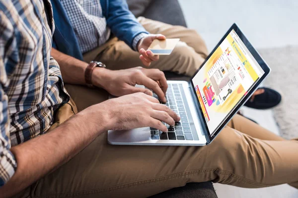 KYIV, UKRAINE - OCTOBER 15, 2019: cropped view of jewish father using laptop with aliexpress website and son holding credit card — Stock Photo