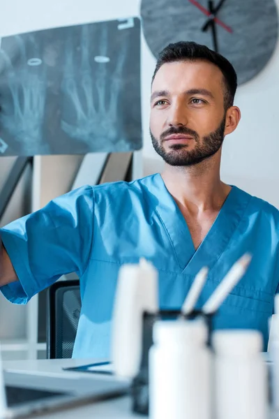 Enfoque selectivo de ortopedista guapo mirando rayos X en el hospital - foto de stock