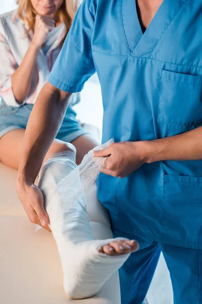 Vista ritagliata di ortopedico mettere benda sulla gamba della donna — Foto stock