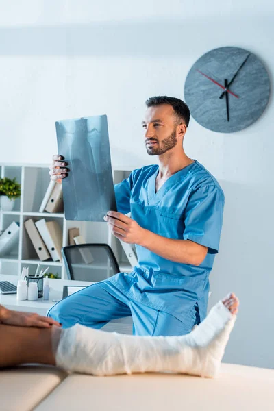 Selektiver Fokus des Orthopäden mit Röntgenaufnahmen in der Nähe verletzter Frau — Stockfoto