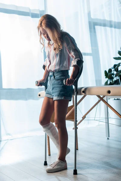 Upset and injured woman using crutches to stand in clinic — Stock Photo