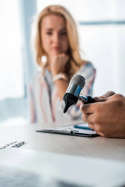 Foyer sélectif du médecin tenant l'otoscope près de la femme en clinique — Photo de stock