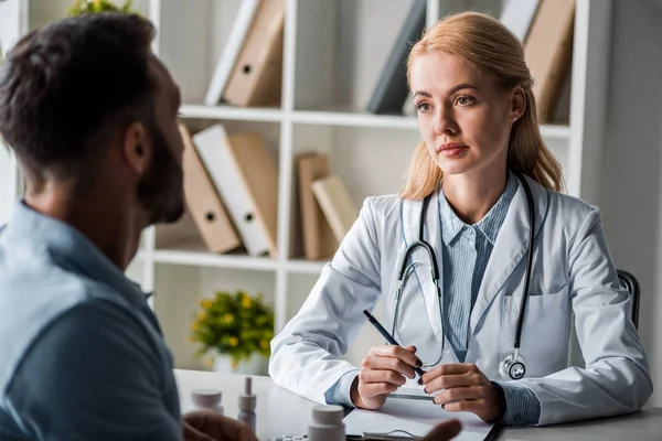 Foyer sélectif de médecin attrayant regardant l'homme dans la clinique — Photo de stock