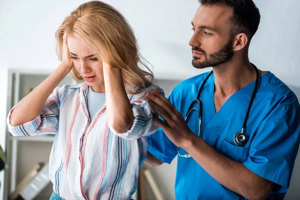 Bonito barbudo médico tocando emocional mulher com dor de cabeça — Fotografia de Stock