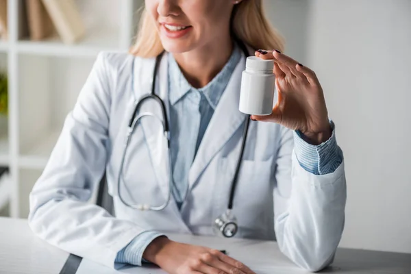 Cropped view of happy doctor holding bottle with pills — Stock Photo