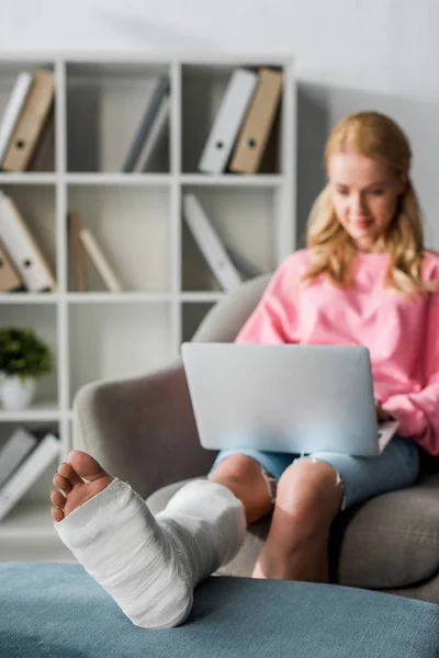 Selective focus of injured woman working from home with laptop — Stock Photo