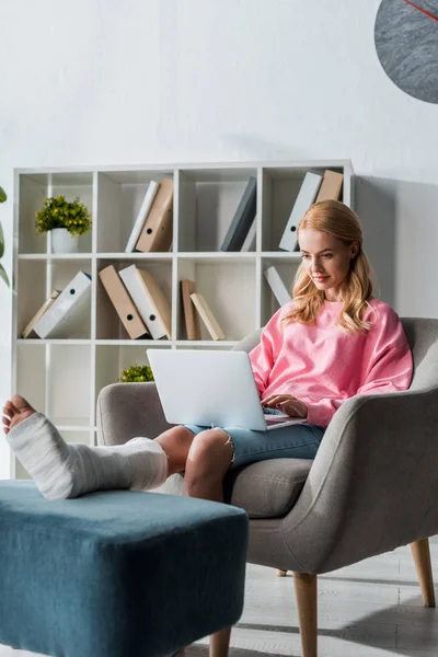 Verletzte Frau arbeitet von zu Hause aus mit Laptop — Stockfoto