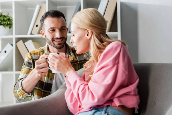 Uomo positivo che dà una tazza di tè alla donna a casa — Foto stock