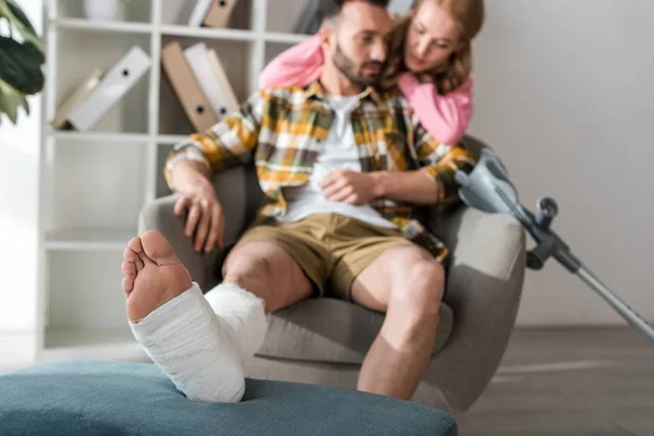 Fuoco selettivo dell'uomo ferito e barbuto seduto vicino alla fidanzata premurosa — Foto stock