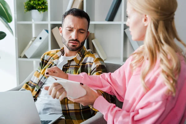 Selective focus of caring woman putting bandage on injured arm of bearded man — Stock Photo