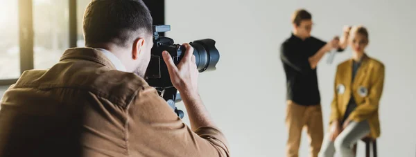 Tiro panorâmico de fotógrafo tirando foto de modelo e cabeleireiro — Fotografia de Stock