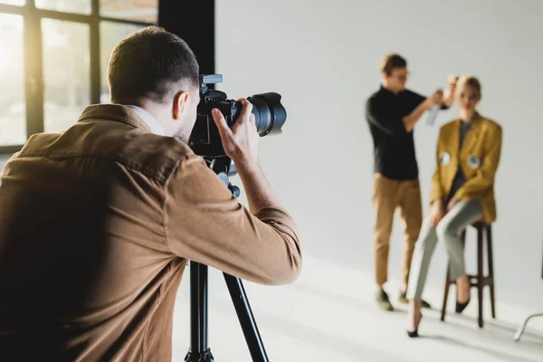 Selective focus of photographer taking photo of model and hairstylist — Stock Photo