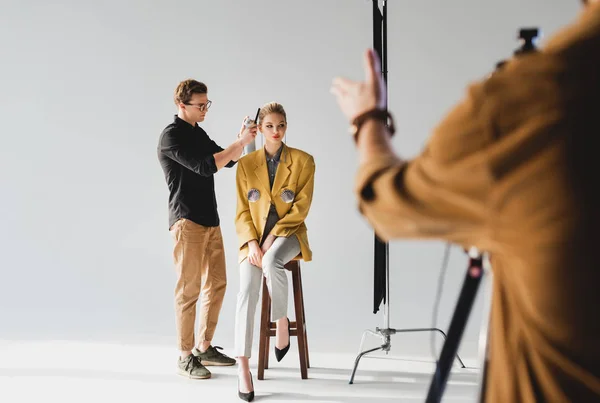 Enfoque selectivo de estilista haciendo peinado a modelo y fotógrafo en el backstage — Stock Photo