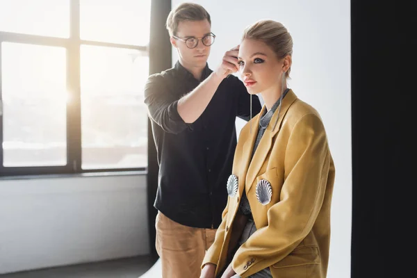 Guapo peluquero haciendo peinado a modelo con estilo en el backstage - foto de stock