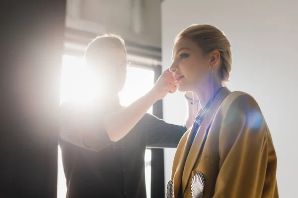 Low angle view of hairstylist doing hairstyle to stylish model on backstage — Stock Photo