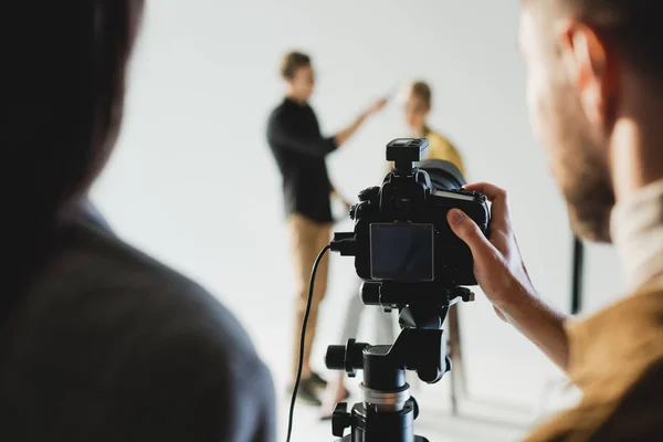 Selective focus of producer and photographer taking photo of model and hairstylist on backstage — Stock Photo