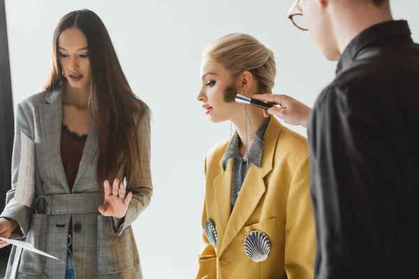 Producteur parler avec modèle et maquilleur faire maquillage sur les coulisses — Photo de stock