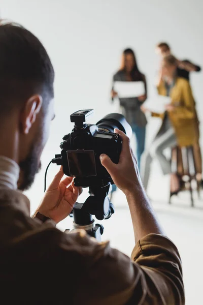 Foco seletivo de fotógrafo que tira foto de produtor, modelo e cabeleireiro — Fotografia de Stock