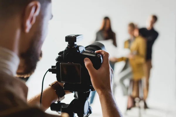 Selective focus of photographer taking photo of producer, model and hairstylist — Stock Photo