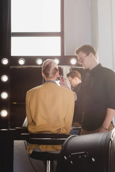 Handsome Makeup Artist doing makeup to model on backstage — Stock Photo