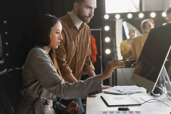 Selektiver Fokus des Produzenten, der auf Computer zeigt und Fotograf, der ihn hinter der Bühne betrachtet — Stockfoto