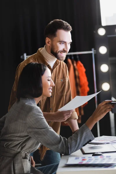 Produttore sorridente e fotografo distogliendo lo sguardo sul backstage — Foto stock