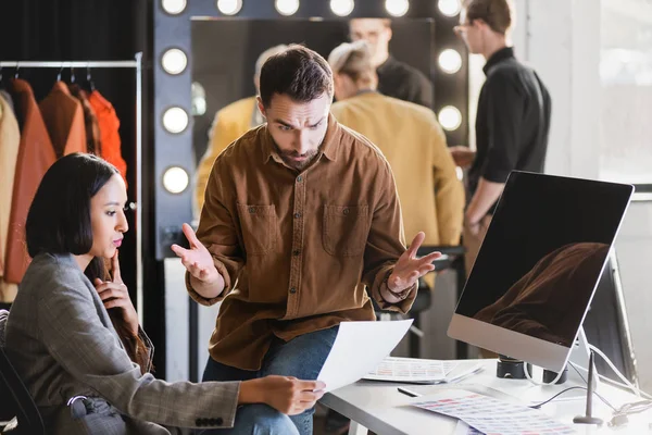 Foyer sélectif du producteur et photographe en colère regardant le papier sur les coulisses — Photo de stock