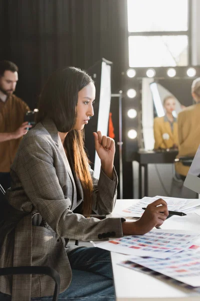 Side view of attractive producer sitting at table and looking away on backstage — Stock Photo