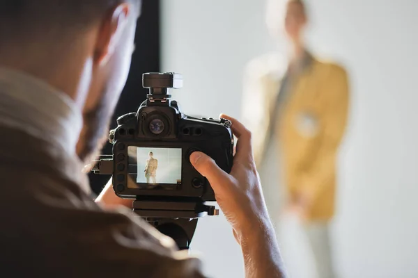 Selective focus of photographer taking photo of model with digital camera on backstage — Stock Photo