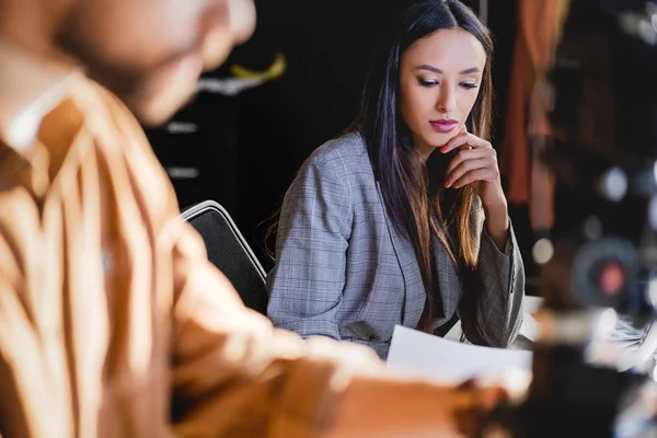 Selective focus of producer looking at paper and photographer on background — Stock Photo