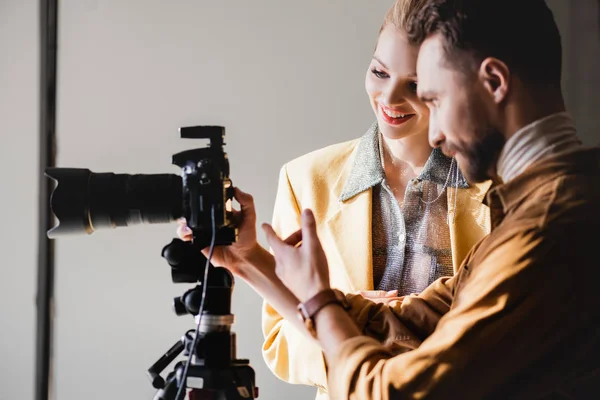 Fotógrafo e modelo sorridente olhando para a câmera digital nos bastidores — Fotografia de Stock