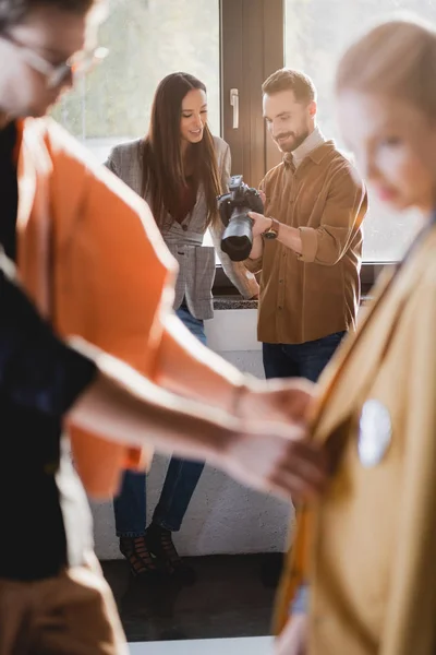 Selektive Fokussierung lächelnder Produzenten und Fotografen auf die Digitalkamera hinter der Bühne — Stockfoto