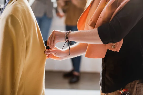 Cropped view of stylist touching jacket on backstage — Stock Photo
