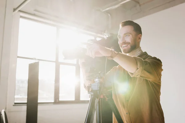 Fotógrafo sorrindo tirar foto com câmera digital e apontando com o dedo nos bastidores — Fotografia de Stock