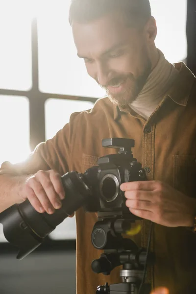 Sorrindo e bonito fotógrafo detalhes da câmera digital nos bastidores — Fotografia de Stock
