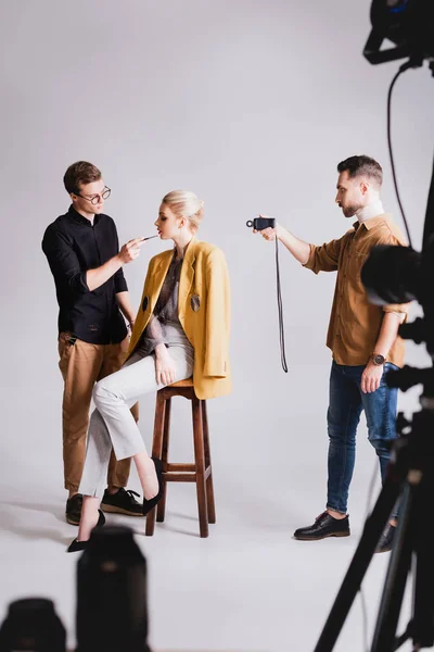 Enfoque selectivo del fotógrafo disparando cómo Maquillaje Artista haciendo maquillaje a modelo con estilo - foto de stock