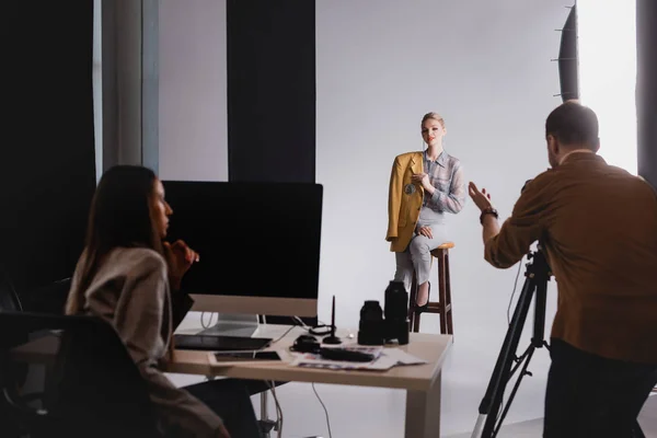 Messa a fuoco selettiva del fotografo parlando con modello sorridente ed elegante — Foto stock