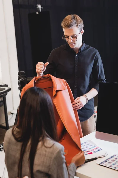 Selective focus of stylist showing jacket to producer on backstage — Stock Photo