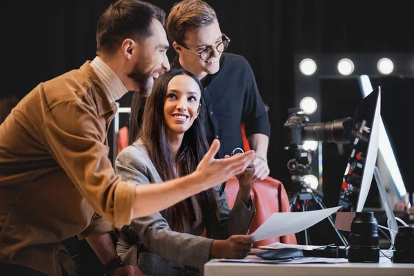 Produtor estilista sorridente e fotógrafo olhando para o computador nos bastidores — Fotografia de Stock