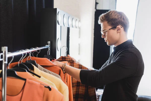 Side view of stylist choosing clothes for photo shoot on backstage — Stock Photo