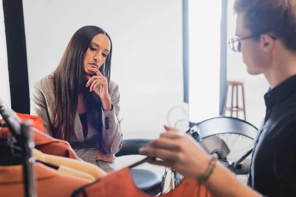 Ausgeschnittene Ansicht der Stylistin, die dem nachdenklichen Produzenten hinter der Bühne Kleidung zeigt — Stockfoto