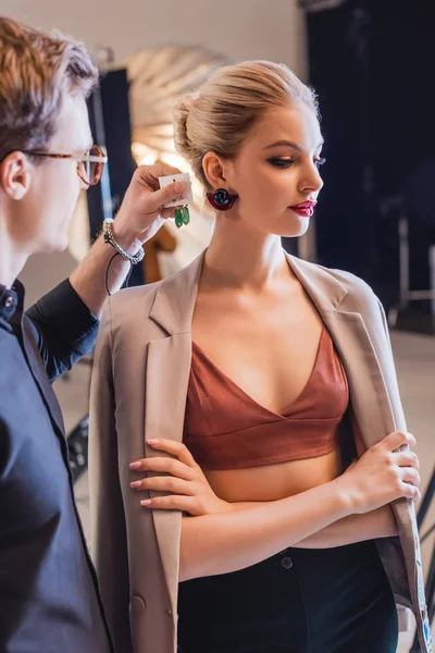 Vue recadrée du styliste choisissant des boucles d'oreilles pour modèle élégant sur les coulisses — Photo de stock