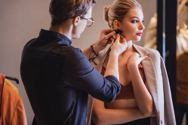 Stilista mettere orecchino sul modello elegante e attraente sul backstage — Foto stock