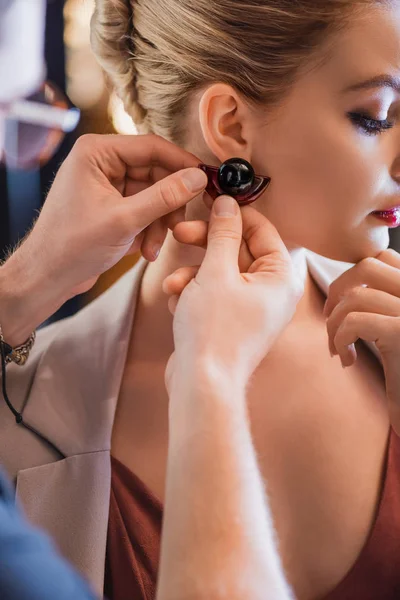 Vista ritagliata di stilista mettendo orecchino sul modello sul backstage — Foto stock