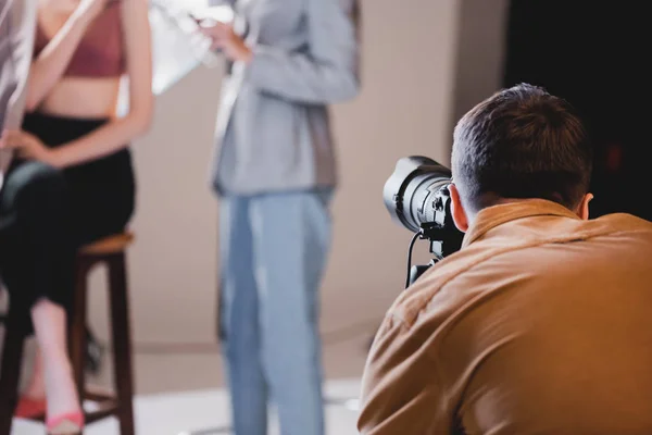 Selective focus of photographer taking photo of model and hairstylist — Stock Photo