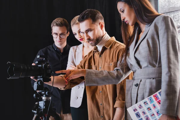 Photographe, mannequin, styliste et producteur regardant un appareil photo numérique dans les coulisses — Photo de stock