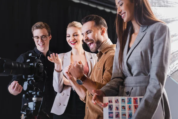 Smiling photographer, model, stylist and producer looking at digital camera on backstage — Stock Photo