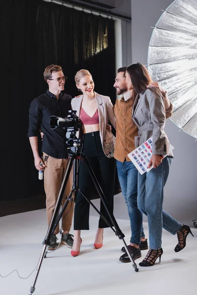 Fotógrafo sonriente, modelo, estilista y productor abrazándose en el backstage - foto de stock