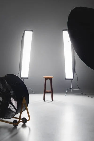 Fan, reflector, wooden stool and lights on backstage in photo studio — Stock Photo